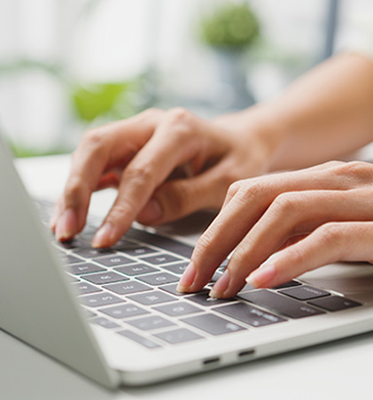 zdjęcie przedstawiające dłonie osoby piszącej na klawiaturze laptopa